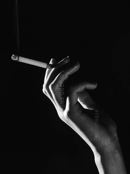 Main de femme avec cigarette et volutes de fume