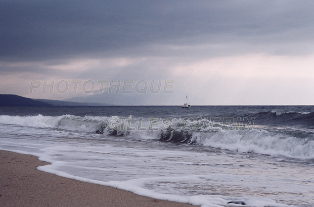 Nostalgie - Mer et ciel gris, et bateau de pche s'loignant vers le large  - Vague dferlant sur plage de sable